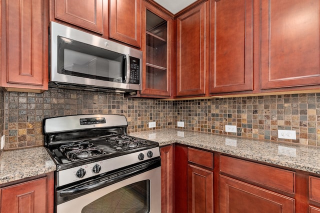 kitchen with decorative backsplash, light stone countertops, and appliances with stainless steel finishes