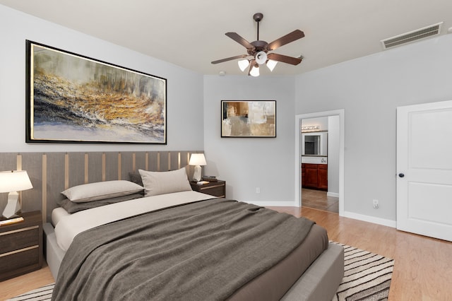 bedroom featuring ceiling fan, light wood-type flooring, and connected bathroom