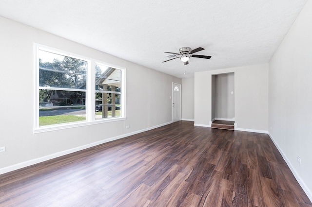 empty room featuring a wealth of natural light, dark hardwood / wood-style flooring, ceiling fan, and a textured ceiling