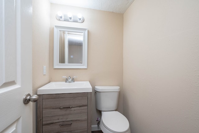 bathroom with vanity, toilet, and a textured ceiling