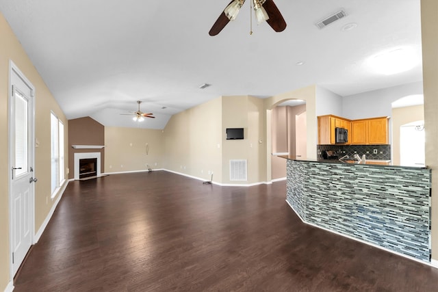 unfurnished living room featuring ceiling fan, dark hardwood / wood-style floors, and vaulted ceiling