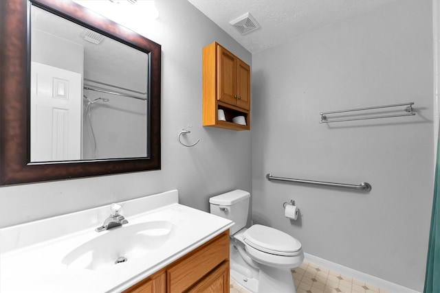 bathroom featuring vanity, a textured ceiling, and toilet