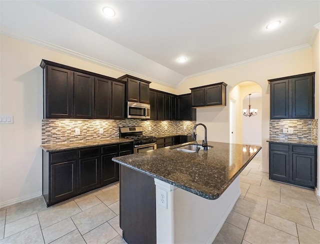 kitchen with a kitchen island with sink, sink, decorative backsplash, dark stone countertops, and stainless steel appliances