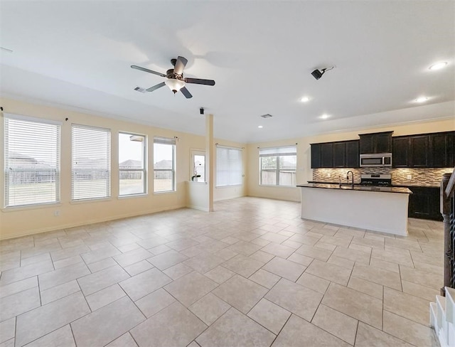 kitchen featuring tasteful backsplash, stainless steel appliances, a wealth of natural light, and an island with sink