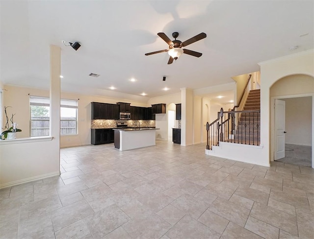 kitchen with tasteful backsplash, ceiling fan, a kitchen island, and ornamental molding