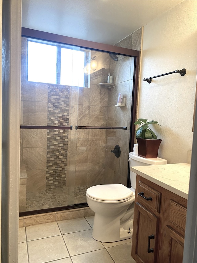 bathroom featuring tile patterned floors, a shower with door, vanity, and toilet