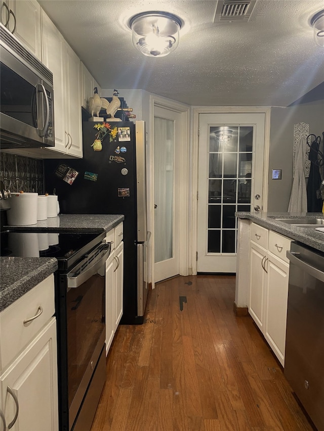 kitchen featuring a textured ceiling, white cabinetry, dark hardwood / wood-style floors, and appliances with stainless steel finishes