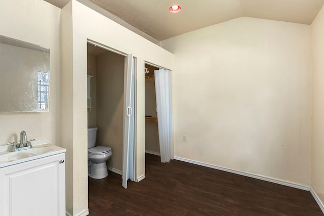 bathroom featuring vanity, wood-type flooring, lofted ceiling, and toilet