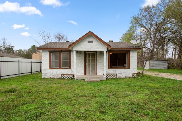 bungalow-style house with a front yard and a storage shed