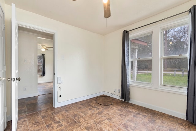 empty room with ceiling fan and a wealth of natural light