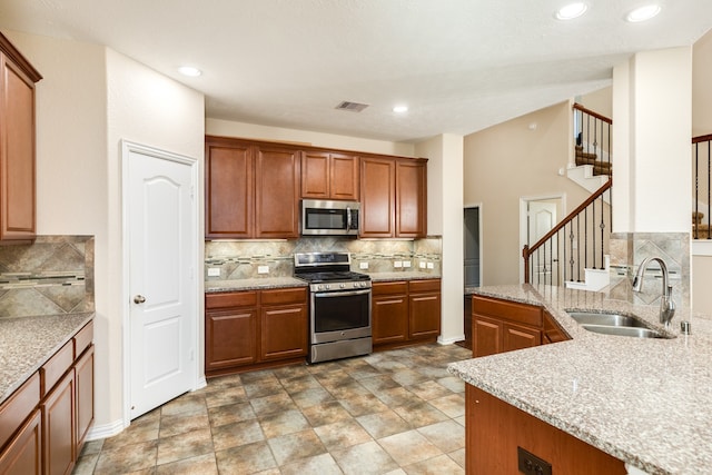 kitchen with decorative backsplash, stainless steel appliances, light stone countertops, and sink