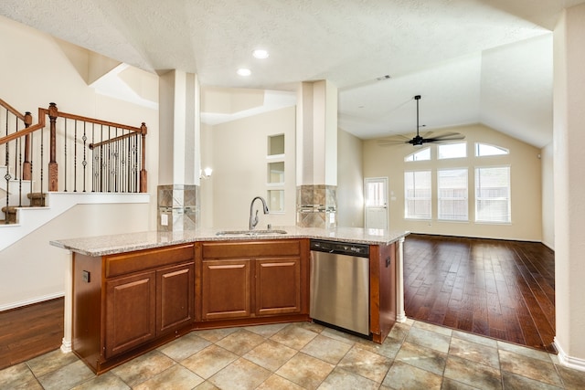 kitchen with light stone countertops, stainless steel dishwasher, a textured ceiling, sink, and light hardwood / wood-style flooring