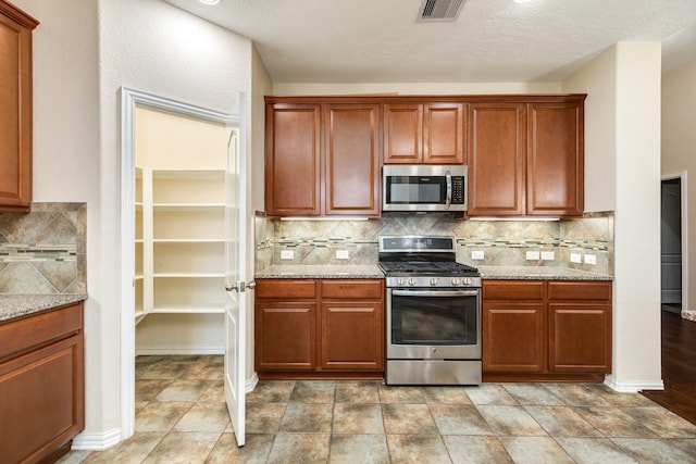 kitchen with tasteful backsplash, light stone countertops, and appliances with stainless steel finishes