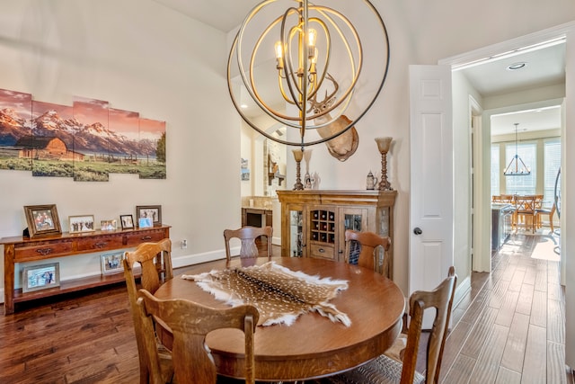 dining space with dark wood-type flooring and an inviting chandelier