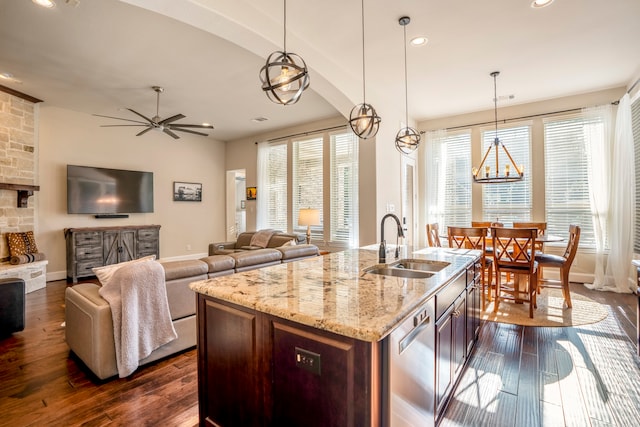 kitchen featuring sink, dark hardwood / wood-style floors, hanging light fixtures, and an island with sink