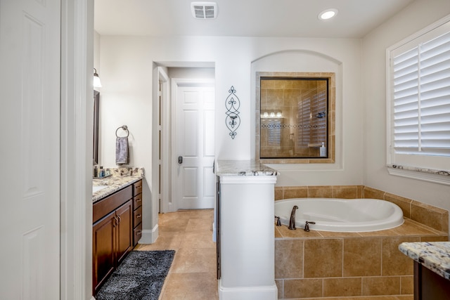 bathroom with vanity and tiled tub