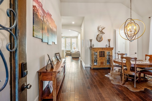 hallway featuring a notable chandelier, dark hardwood / wood-style flooring, and lofted ceiling