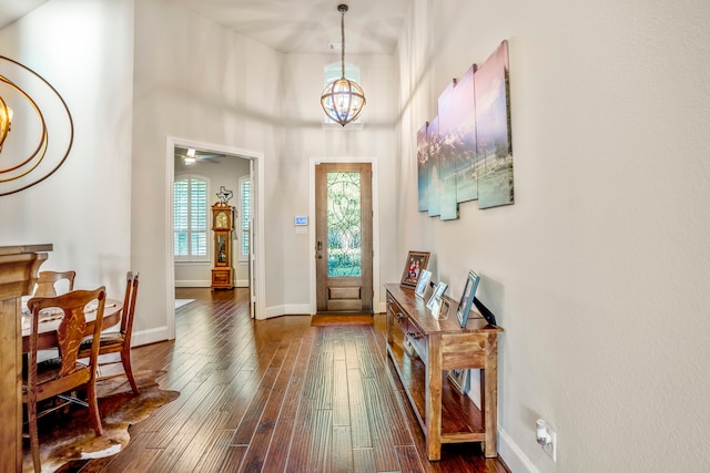 entryway featuring dark hardwood / wood-style floors, a towering ceiling, and ceiling fan with notable chandelier