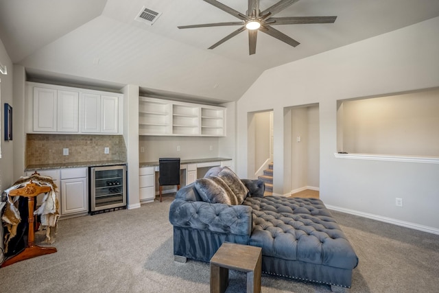 carpeted living room with ceiling fan, beverage cooler, and lofted ceiling