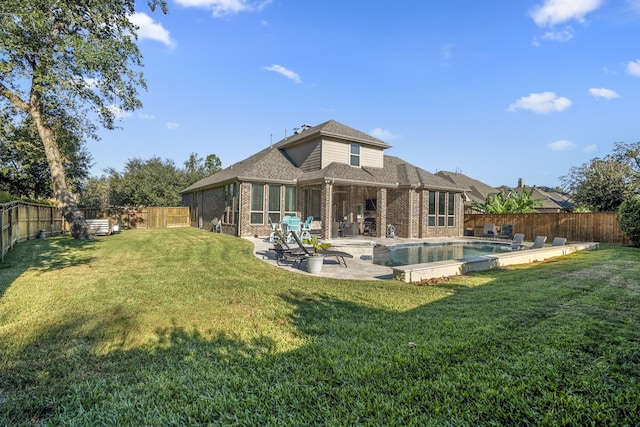 rear view of property with a lawn, a fenced in pool, and a patio