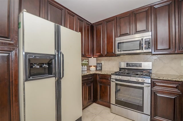 kitchen with decorative backsplash, light tile patterned floors, light stone countertops, and appliances with stainless steel finishes