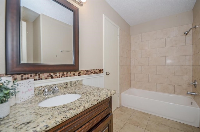 bathroom featuring tile patterned floors, vanity, a textured ceiling, and tiled shower / bath