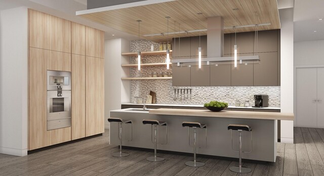 2240 Mimosa Dr Unit 5W, Houston, TX 77019 - kitchen featuring backsplash, modern cabinets, wood finished floors, and an island with sink
