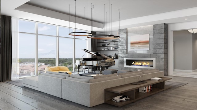 living room featuring expansive windows, a tray ceiling, a tiled fireplace, and wood finished floors