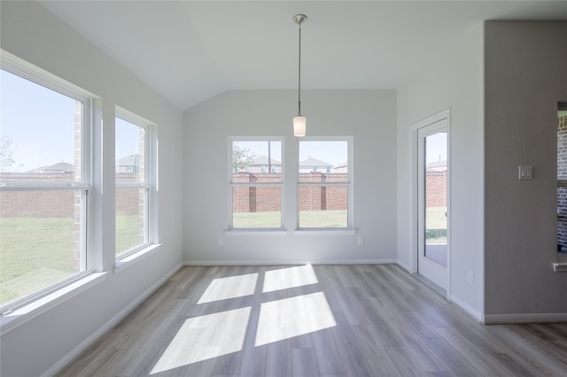 unfurnished dining area featuring light hardwood / wood-style floors, lofted ceiling, and a wealth of natural light