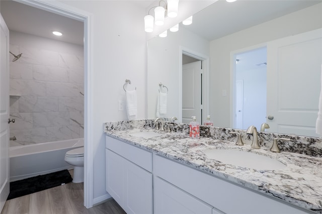 full bathroom with toilet, vanity, hardwood / wood-style flooring, and tiled shower / bath combo