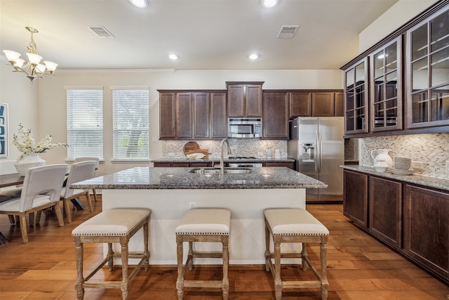 kitchen featuring hardwood / wood-style floors, pendant lighting, dark stone counters, sink, and appliances with stainless steel finishes