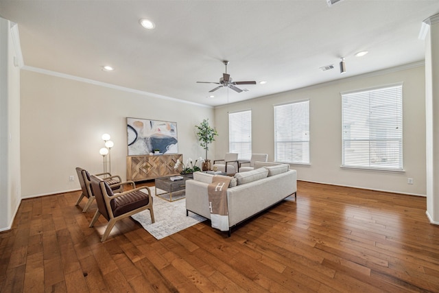 living room with a healthy amount of sunlight, crown molding, and dark wood-type flooring