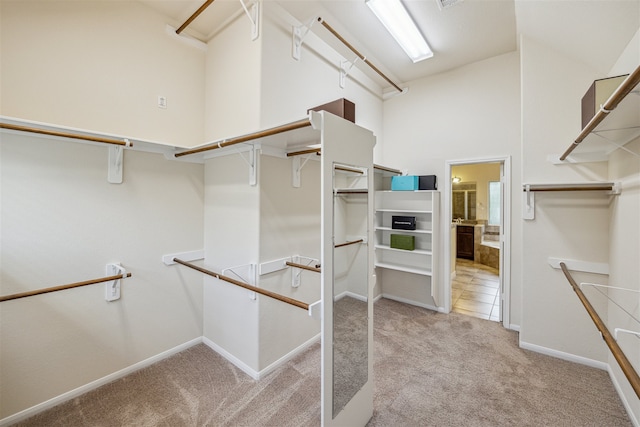 walk in closet featuring a towering ceiling and light colored carpet