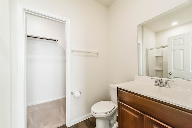 bathroom with toilet, vanity, wood-type flooring, and walk in shower