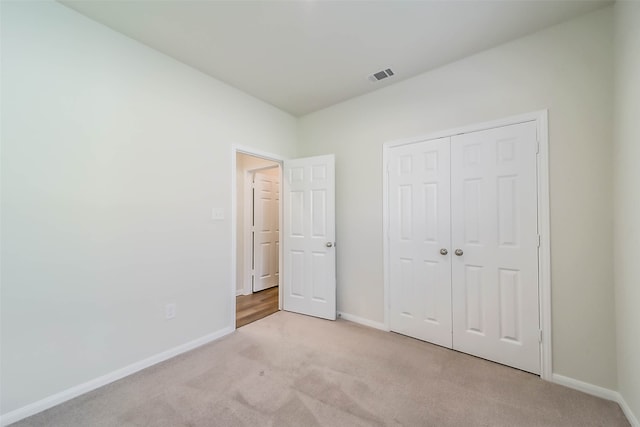 unfurnished bedroom featuring a closet and light colored carpet