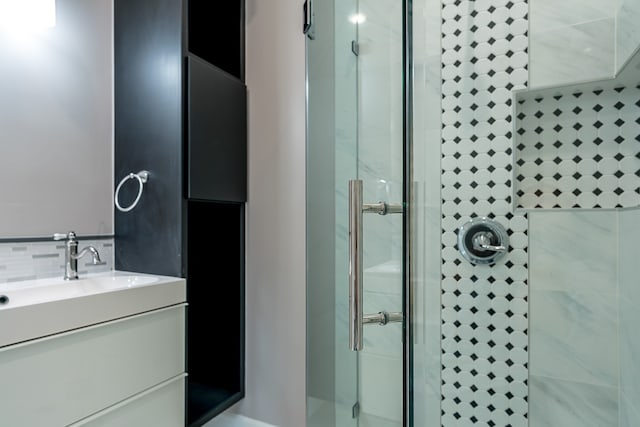 bathroom with decorative backsplash, vanity, and an enclosed shower