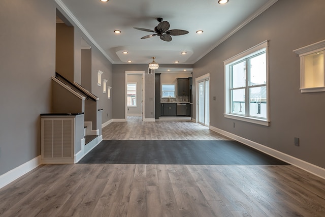 unfurnished living room with hardwood / wood-style floors, plenty of natural light, ornamental molding, and ceiling fan