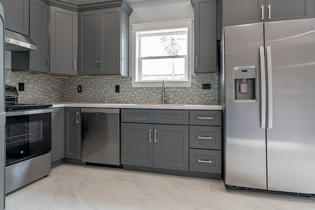 kitchen with gray cabinetry, sink, ventilation hood, decorative backsplash, and appliances with stainless steel finishes