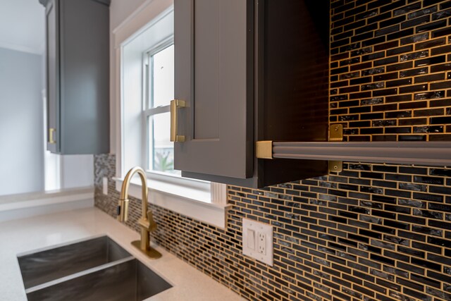 kitchen featuring backsplash, gray cabinetry, and sink