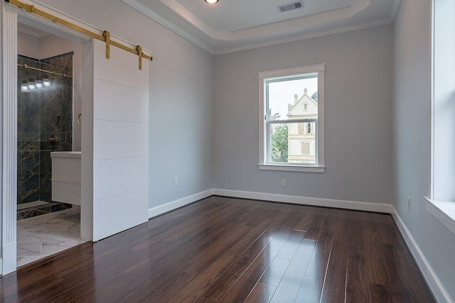 unfurnished room with dark hardwood / wood-style floors, a barn door, and ornamental molding