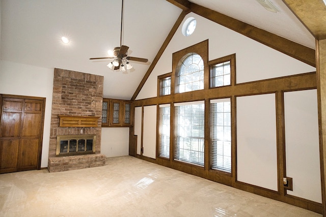 unfurnished living room featuring ceiling fan, a brick fireplace, beamed ceiling, high vaulted ceiling, and light carpet