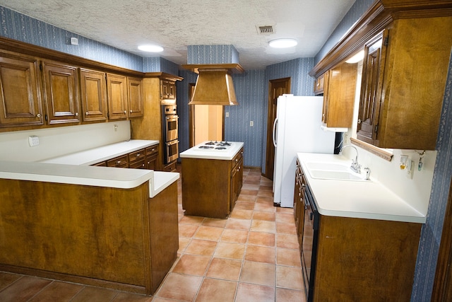 kitchen with white appliances, sink, a textured ceiling, a kitchen island, and kitchen peninsula