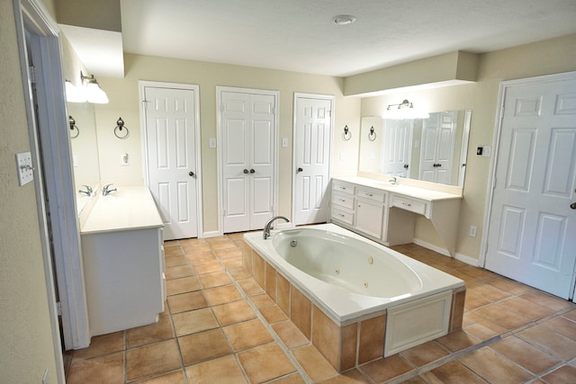 bathroom featuring tile patterned floors, vanity, a textured ceiling, and tiled bath