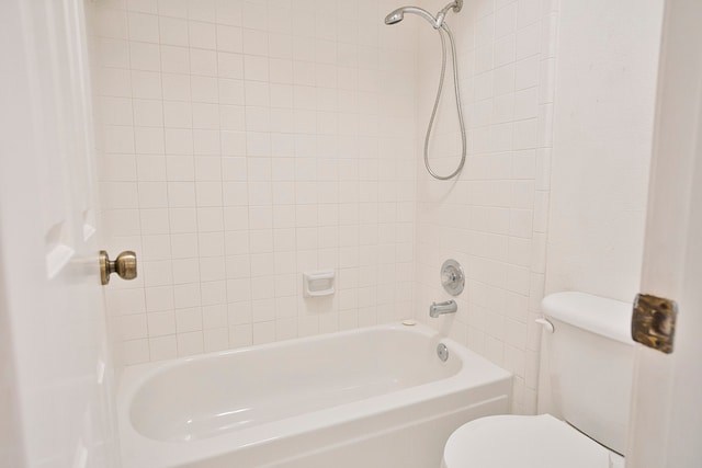 bathroom with toilet and tiled shower / bath