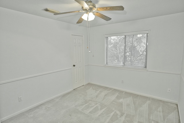 spare room with ceiling fan and light carpet