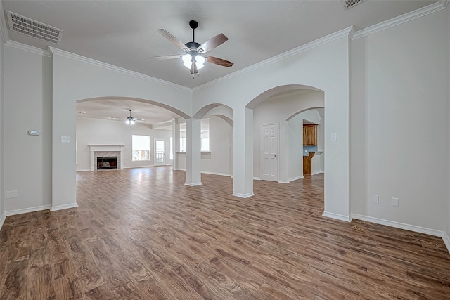 unfurnished living room featuring dark hardwood / wood-style floors, ceiling fan, ornamental molding, and a fireplace