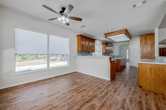 kitchen with dark hardwood / wood-style floors, ceiling fan, kitchen peninsula, and a textured ceiling