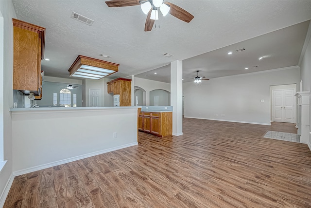 unfurnished living room featuring wood-type flooring, a textured ceiling, and crown molding