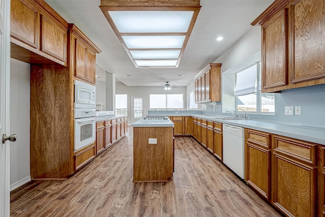 kitchen with a kitchen island, white appliances, a wealth of natural light, and light hardwood / wood-style flooring