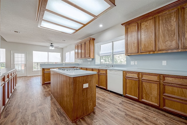 kitchen featuring a center island, white dishwasher, a textured ceiling, and light hardwood / wood-style flooring